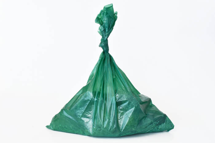 green trash bag full of cat poop and litter